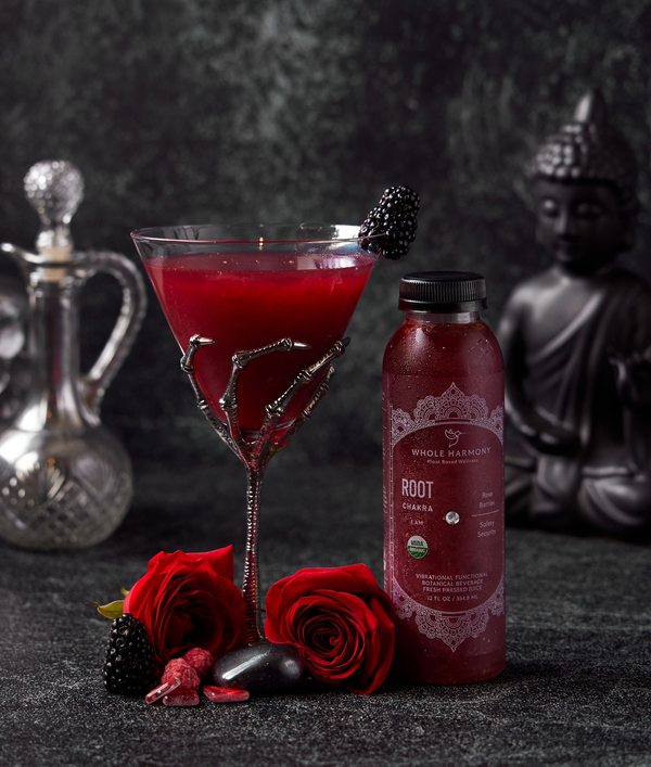 Root Chakra balancing beverage next to a mixed drink, roses, berries and stones. A buddha in the background.